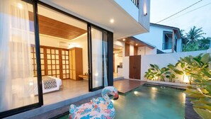 Ett modernt hus med en swimmingpool, en uppblåsbar svan och utsikt över havet.