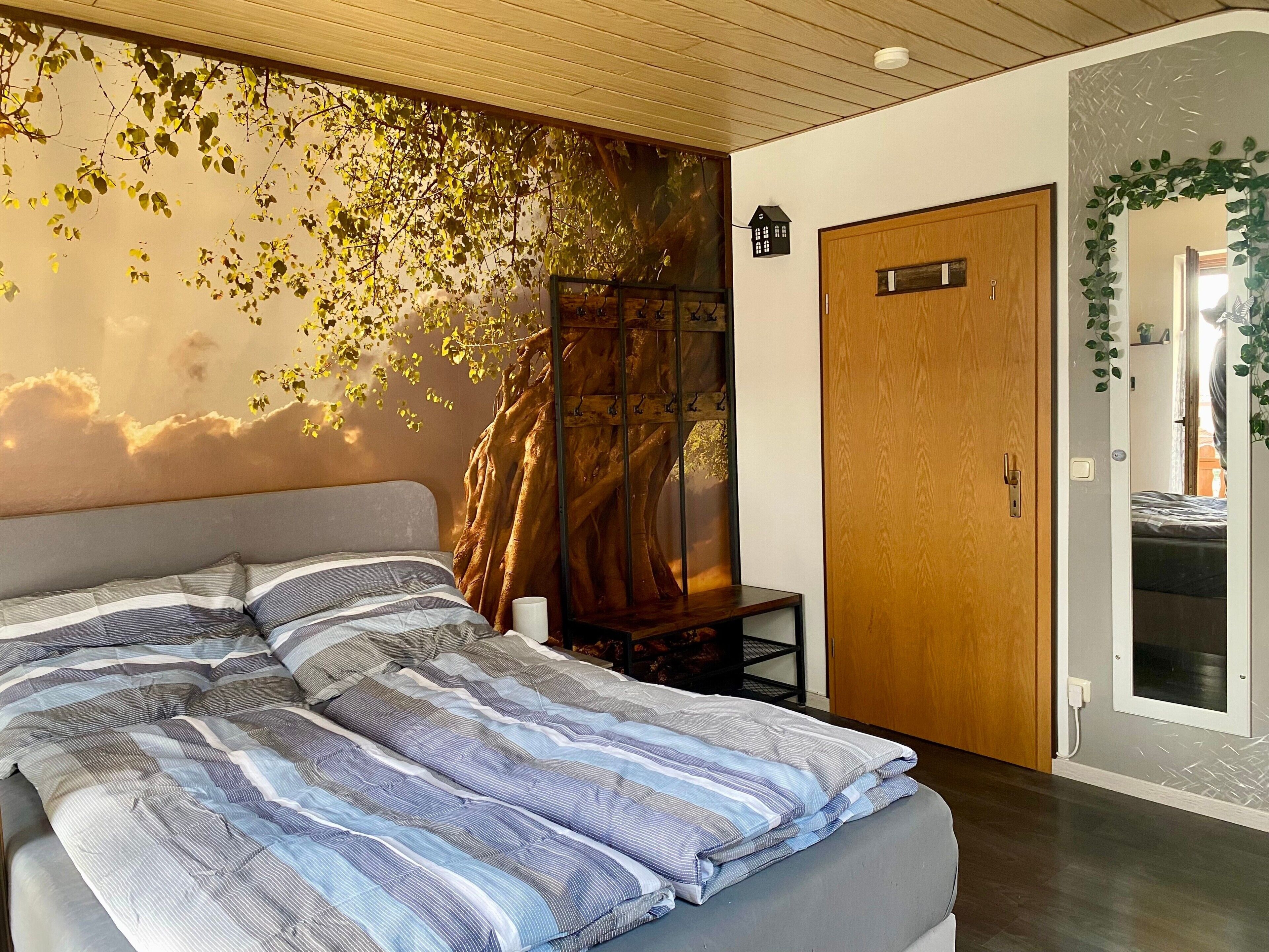 Ein Schlafzimmer mit einem Bett, einer Holztür und einer Wand mit einer Ast-Motiv.