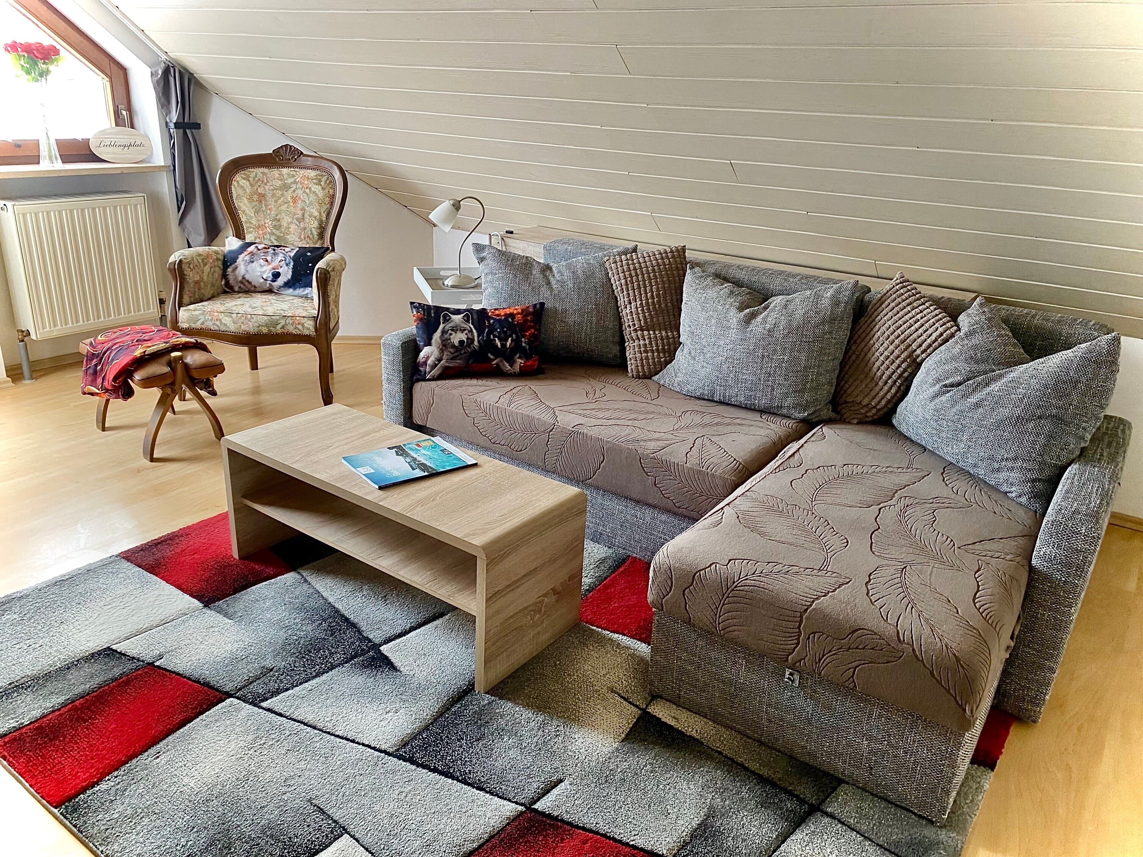 A cozy living room with a sofa, a chair, a coffee table, and a patterned rug.