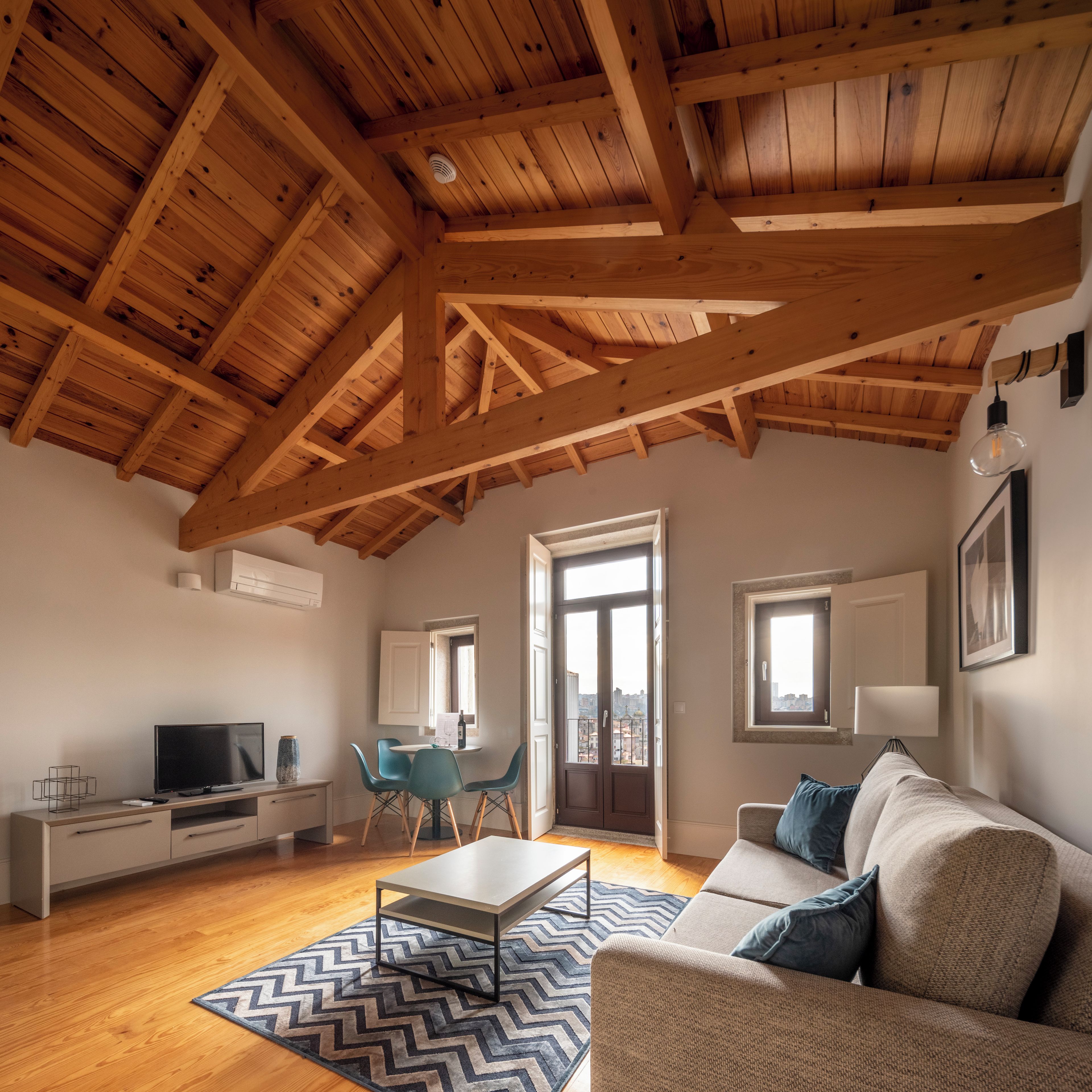 A modern living room with a wooden ceiling, a sofa, a TV, and a dining area.