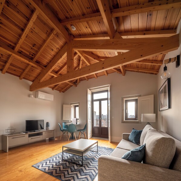 Una sala de estar moderna con techo de madera, un sofá, un televisor y un comedor.