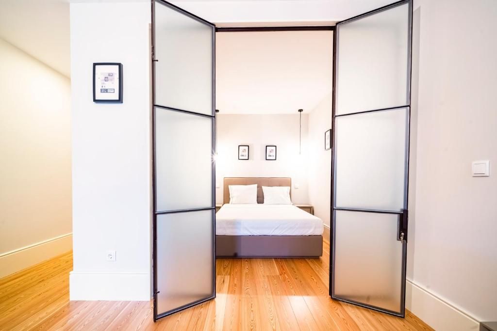 Un dormitorio con cama, mesita de noche e iluminación montada en la pared.