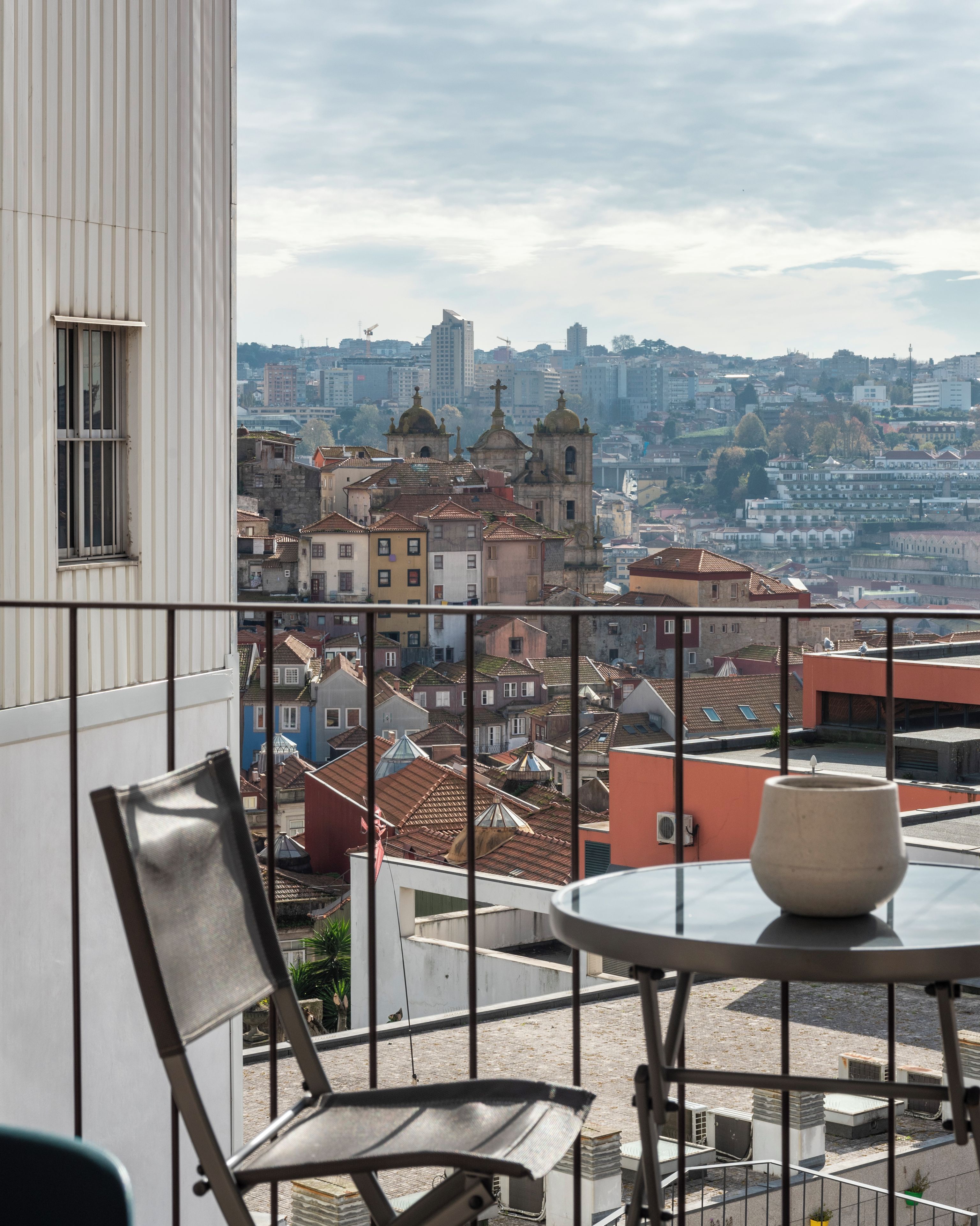 Un balcón con vistas a un paisaje urbano, que incluye edificios y una iglesia.