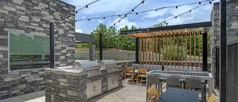 An outdoor patio with stone walls, a barbecue grill, and string lights.