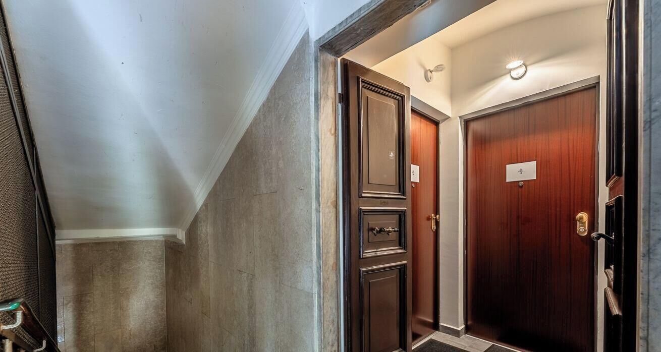 A hallway with a wooden door, a metal door, and a wall with a textured finish.