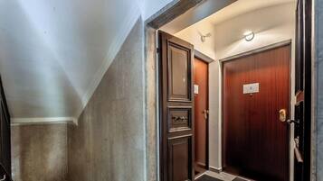 A hallway with a wooden door, a metal door, and a wall with a textured finish.