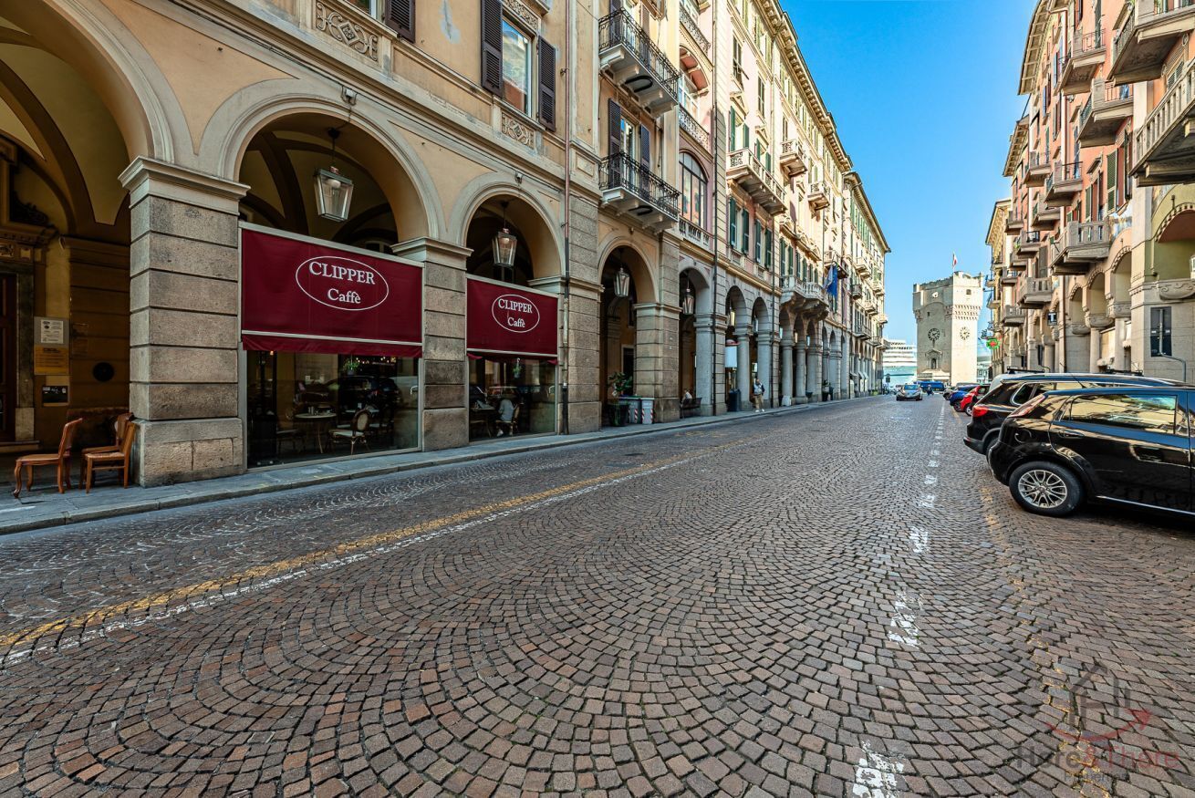 A cobblestone street with buildings featuring arched windows and signage for 'CLIPPER Caffe'.