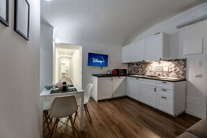 A compact kitchen with white cabinets, a black countertop, and a tiled backsplash.
