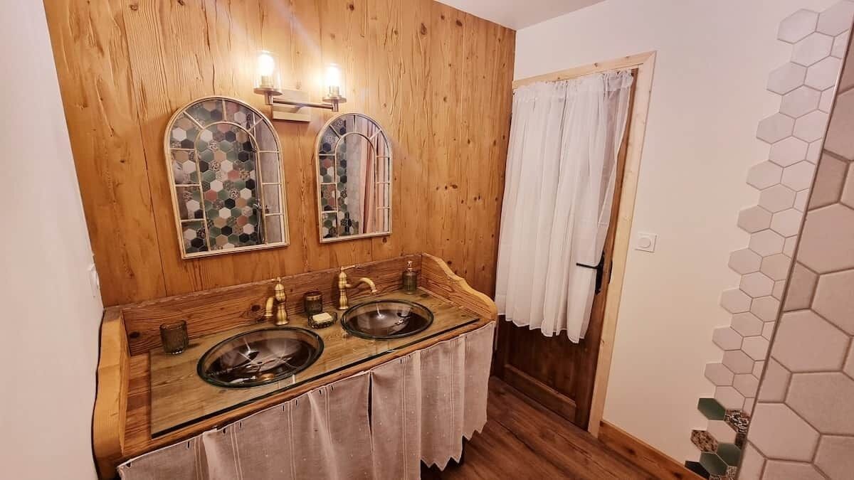 A bathroom with wooden paneling, two sinks, a mirror, and a shower curtain.