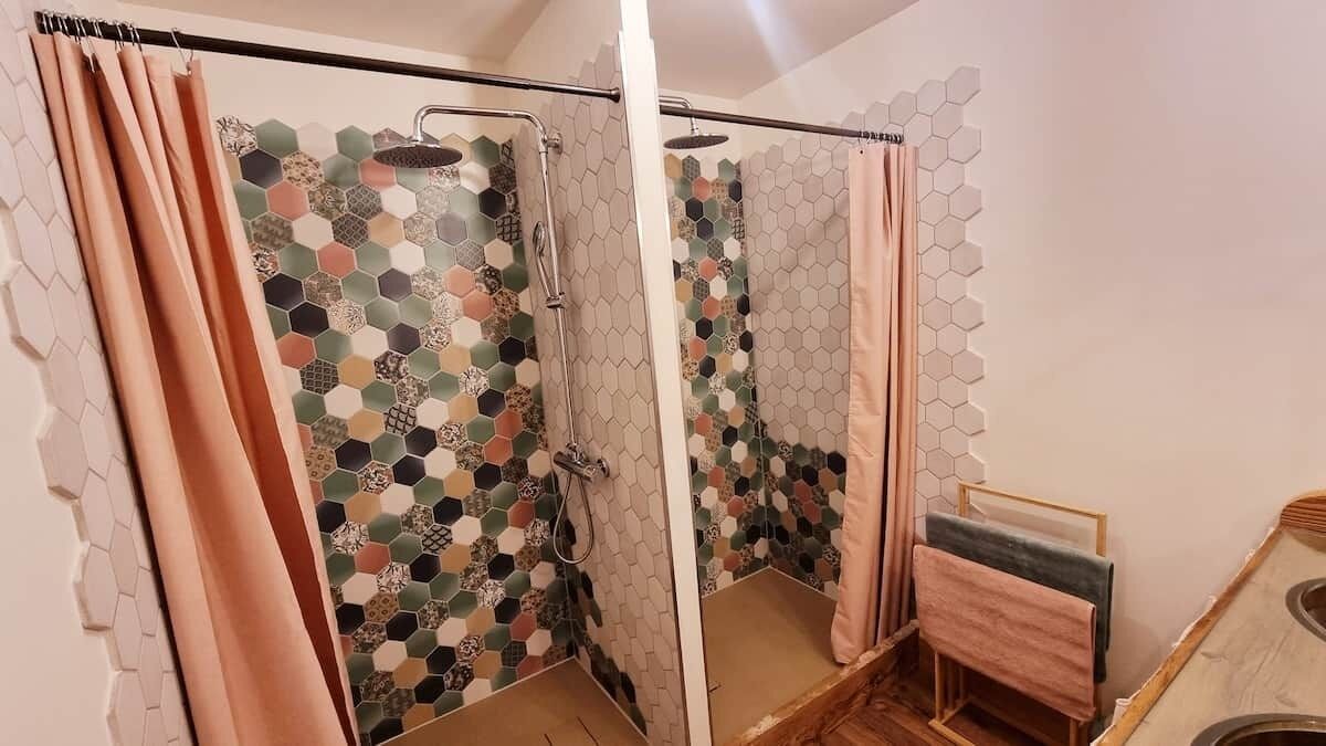 Et badeværelse med bruser, spejl og håndklædestige.