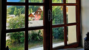 Suuri ikkuna, josta avautuu näkymä metsäiselle vuoristoalueelle ja punaiseen rakennukseen.
