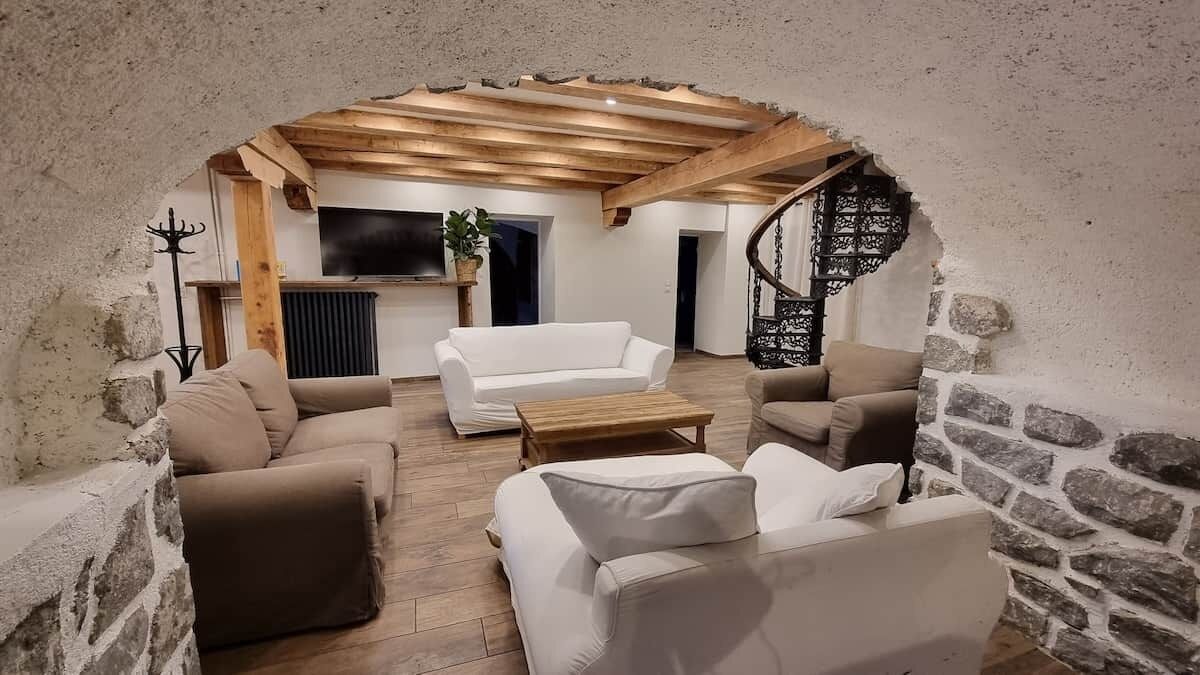 Uma sala de estar aconchegante com um sofá branco, poltronas bege e uma mesa de centro de madeira.