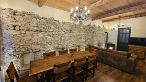 A rustic interior with a stone wall, wooden dining table, and a cozy seating area.