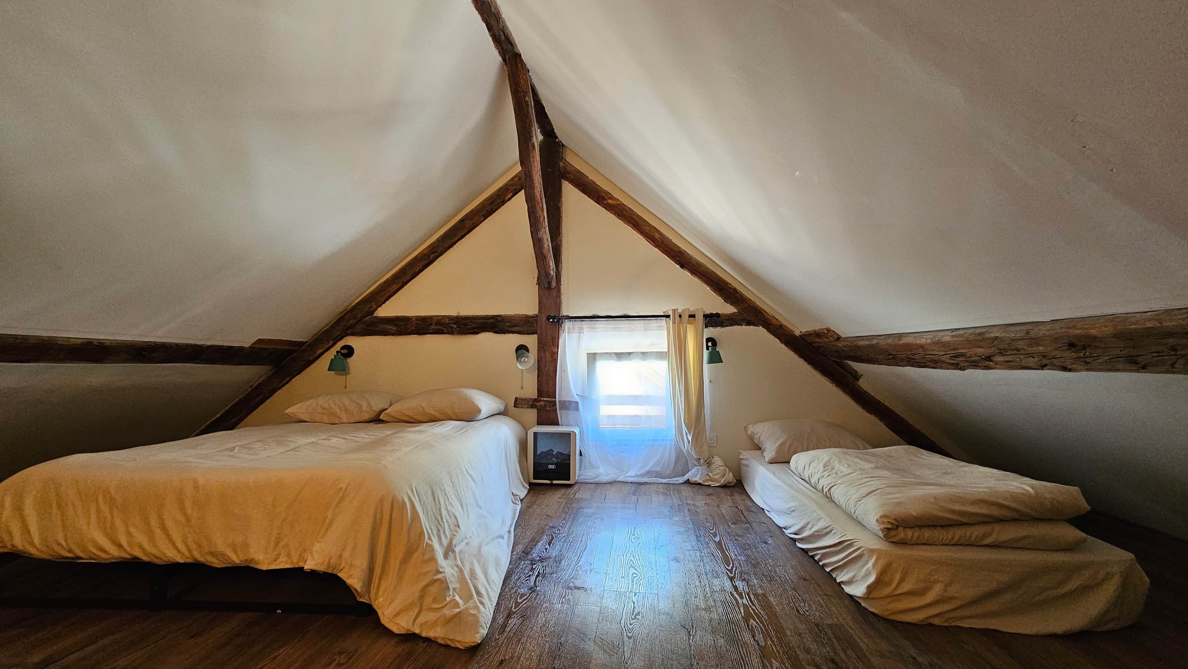 Een kamer met twee bedden, een raam met gordijnen en een houten vloer.
