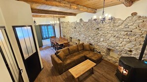 A cozy living room with a stone wall, wooden furniture, and a fireplace.