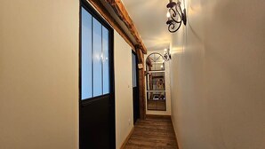 Un couloir doté d’un plancher en bois, d’une grande fenêtre et d’un luminaire fixé au mur.
