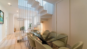 Un comedor moderno con una mesa y sillas de vidrio, una escalera y vistas al exterior.