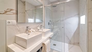 A modern bathroom with two sinks, a shower, and a large mirror.