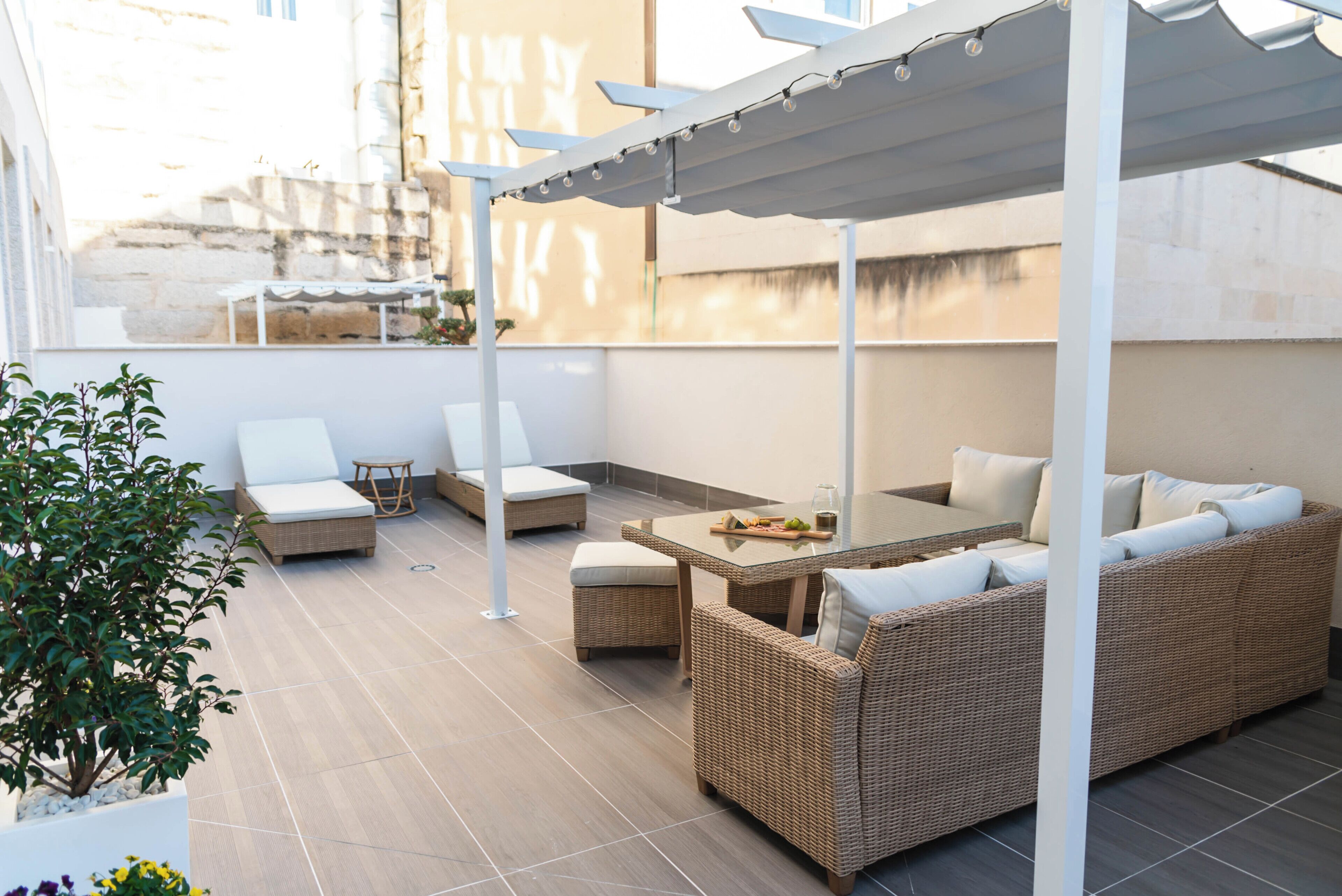 A covered outdoor seating area with wicker furniture and a glass table.