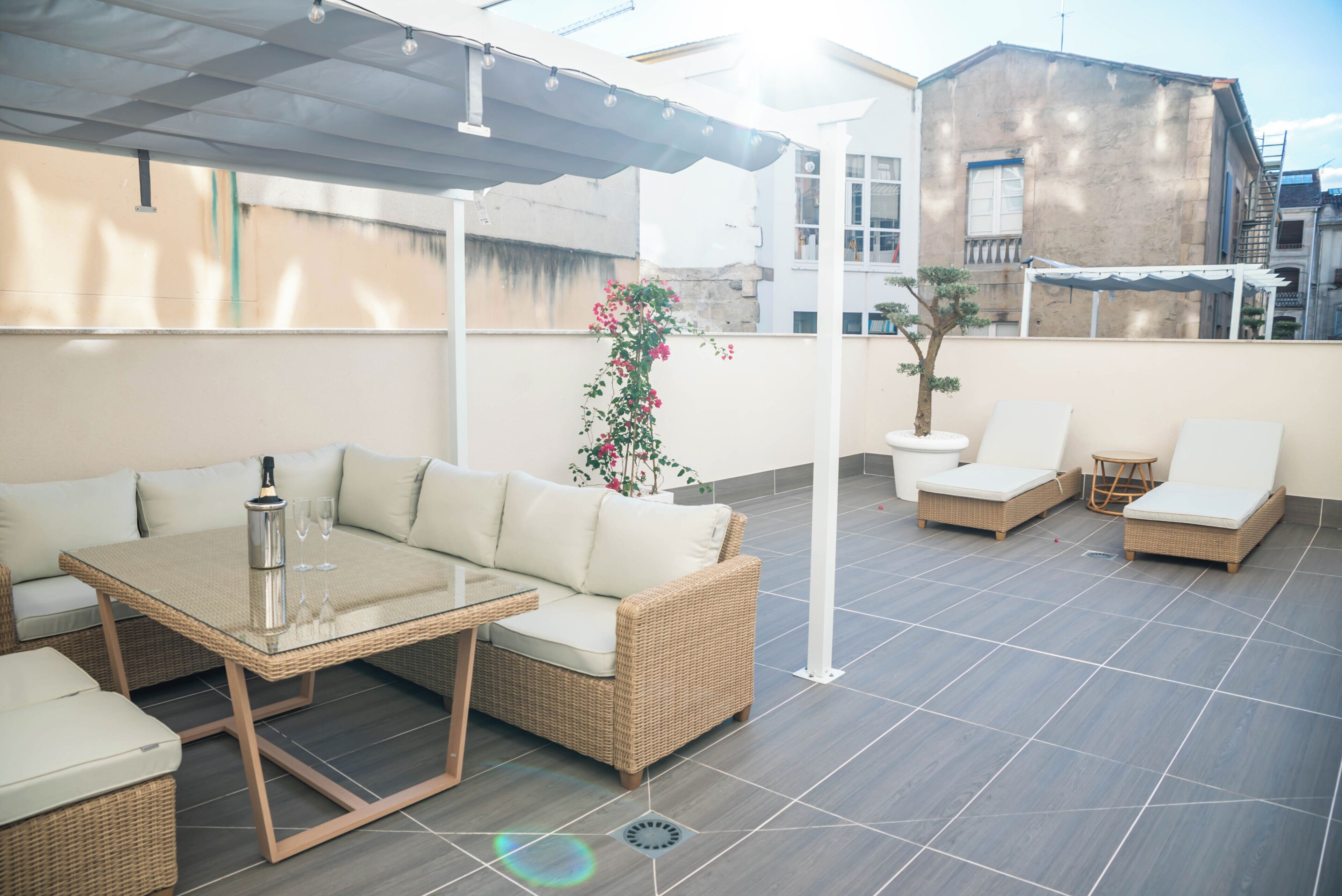 An outdoor patio with a glass-top table, wicker furniture, and a potted plant.