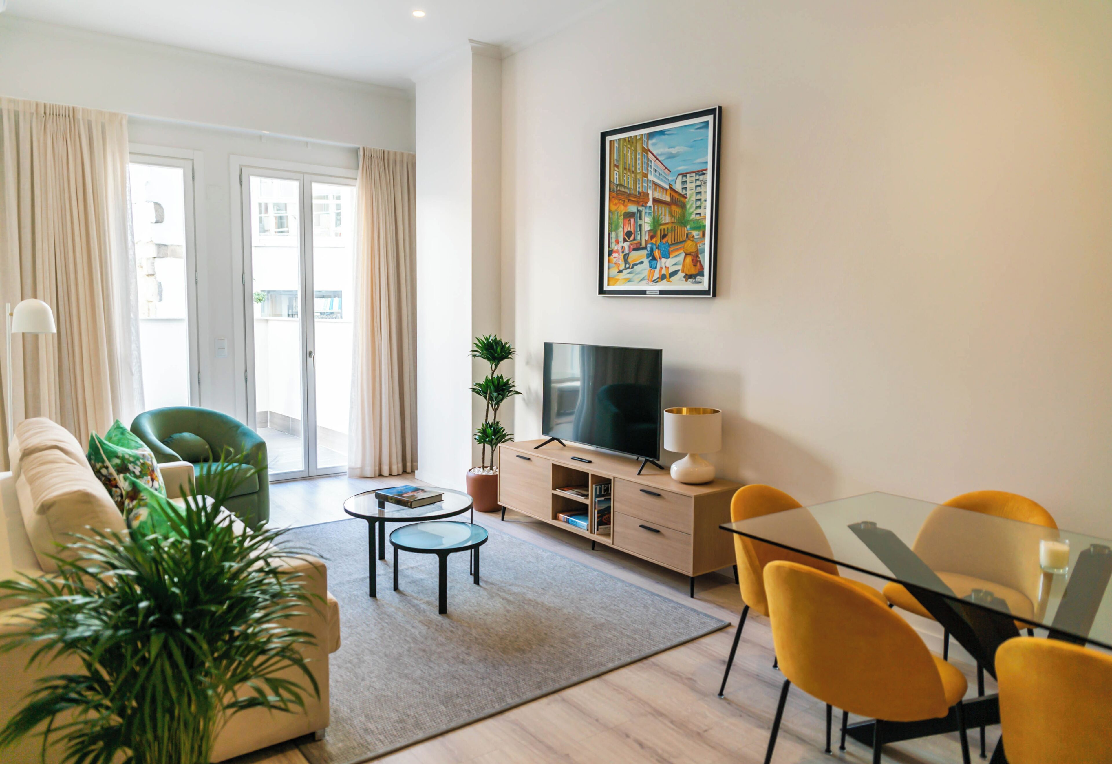 A modern living room with a sofa, chairs, a coffee table, a TV, and a painting on the wall.