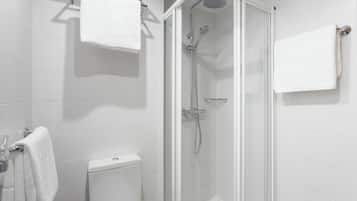 Dusche mit Glastür, Toilette und Handtuchhalter.