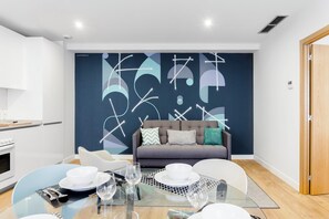 A modern living room with a dining area, a sofa, and a decorative wall. - Morar Apartments Malasaña (Madrid)
