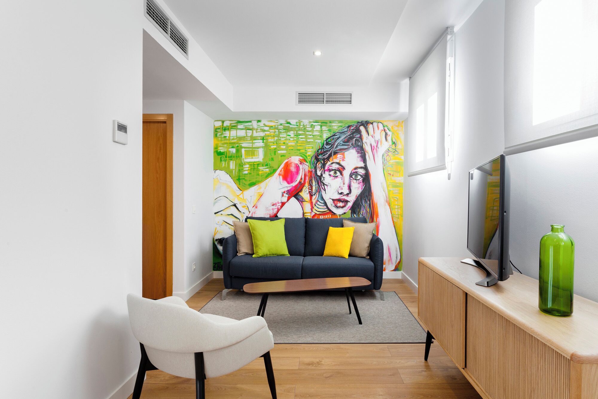 A modern living room with a sofa, a television, and a vibrant abstract painting on the wall.