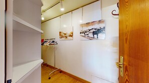 A hallway with a wooden door, a coat rack with clothes, and two framed pictures on the wall. - 3-room apartment with approx. (St. Moritz)