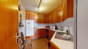 A compact kitchen with wooden cabinets, a built-in oven, and a stainless steel sink. - 3-room apartment with approx. (St. Moritz)