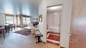 A spacious living area with a dining table, chairs, a sofa, a fireplace, and a view through a glass door. - 3-room apartment with approx. (St. Moritz)