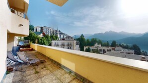 A balcony with outdoor furniture, a view of a town with buildings and mountains in the background. - 3-room apartment with approx. (St. Moritz)