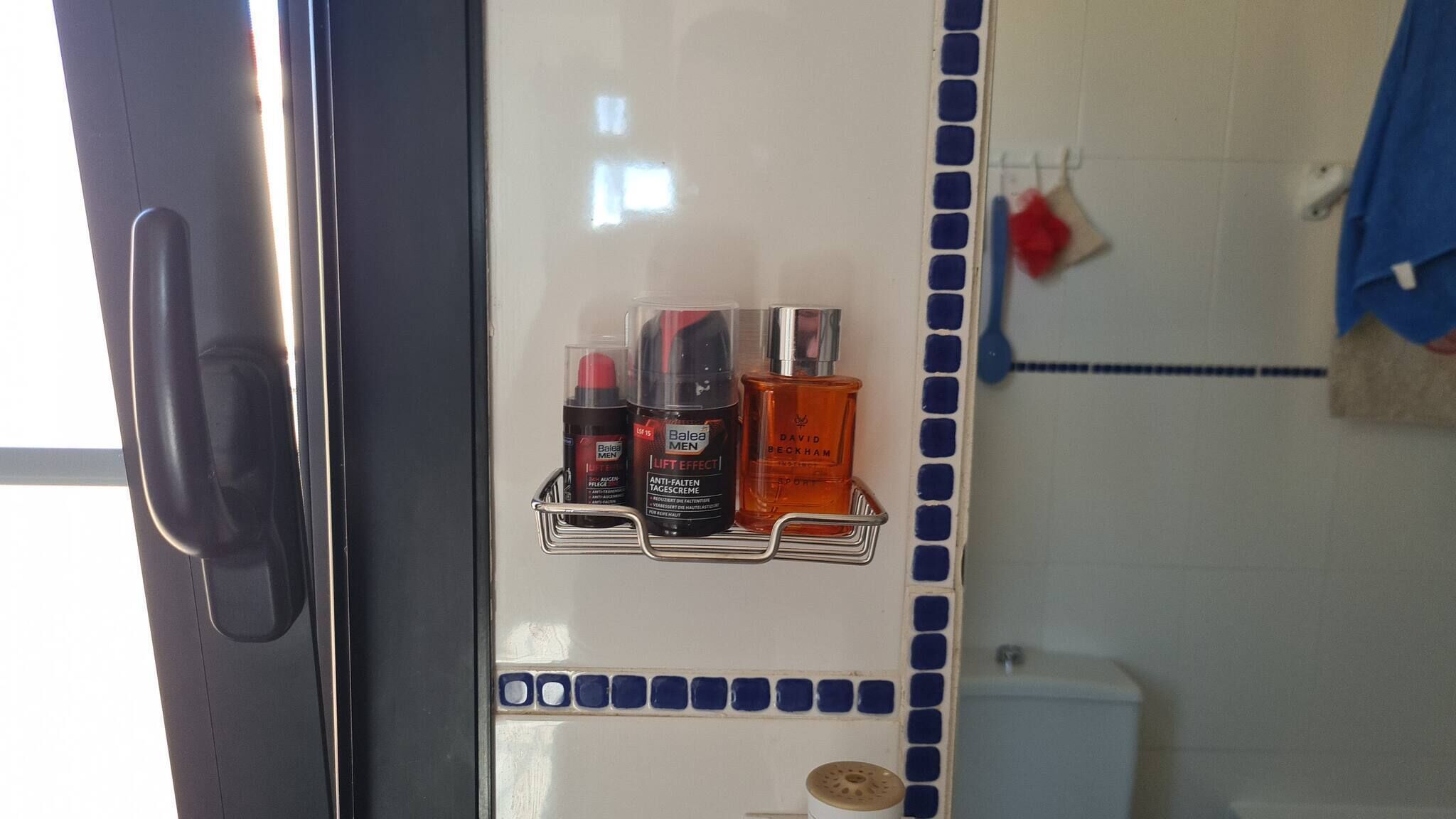Un baño con dispensador de gel hidroalcohólico, dispensador de jabón y una botella de jabón en un estante.