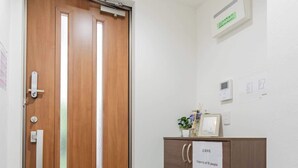 Une porte en bois avec une poignée verticale, un panneau indiquant la capacité maximale, un petit placard avec un panneau, et un panneau indiquant la sortie de secours au-dessus de la porte.