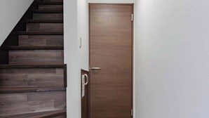 Un couloir avec un escalier en bois, une porte en bois et un mur blanc.