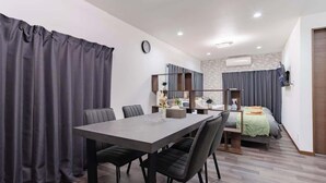 Une chambre moderne équipée d’une table à manger, de chaises, d’un lit et d’un téléviseur.