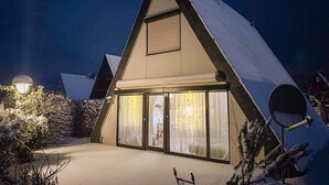Un bâtiment de forme triangulaire, avec un toit enneigé, de grandes portes vitrées et une antenne parabolique.