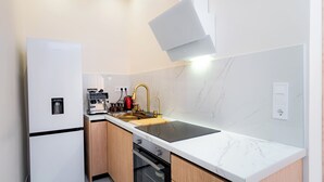 Una cocina moderna con horno empotrado, cafetera y lavamanos con grifo dorado.