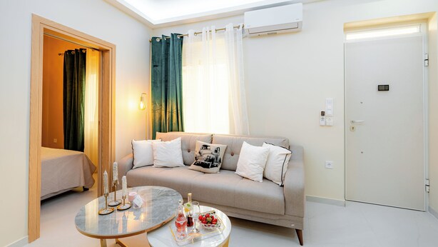 Una habitación de hotel moderna con sofá, una mesa redonda con una bandeja de comida, una cama y una puerta.