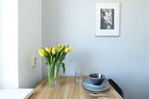 A dining table with a vase of yellow tulips, a glass, and a blue bowl on plates. - Stylish Studio Apt in Kemi | Peaceful Neighborhood (Kemi)