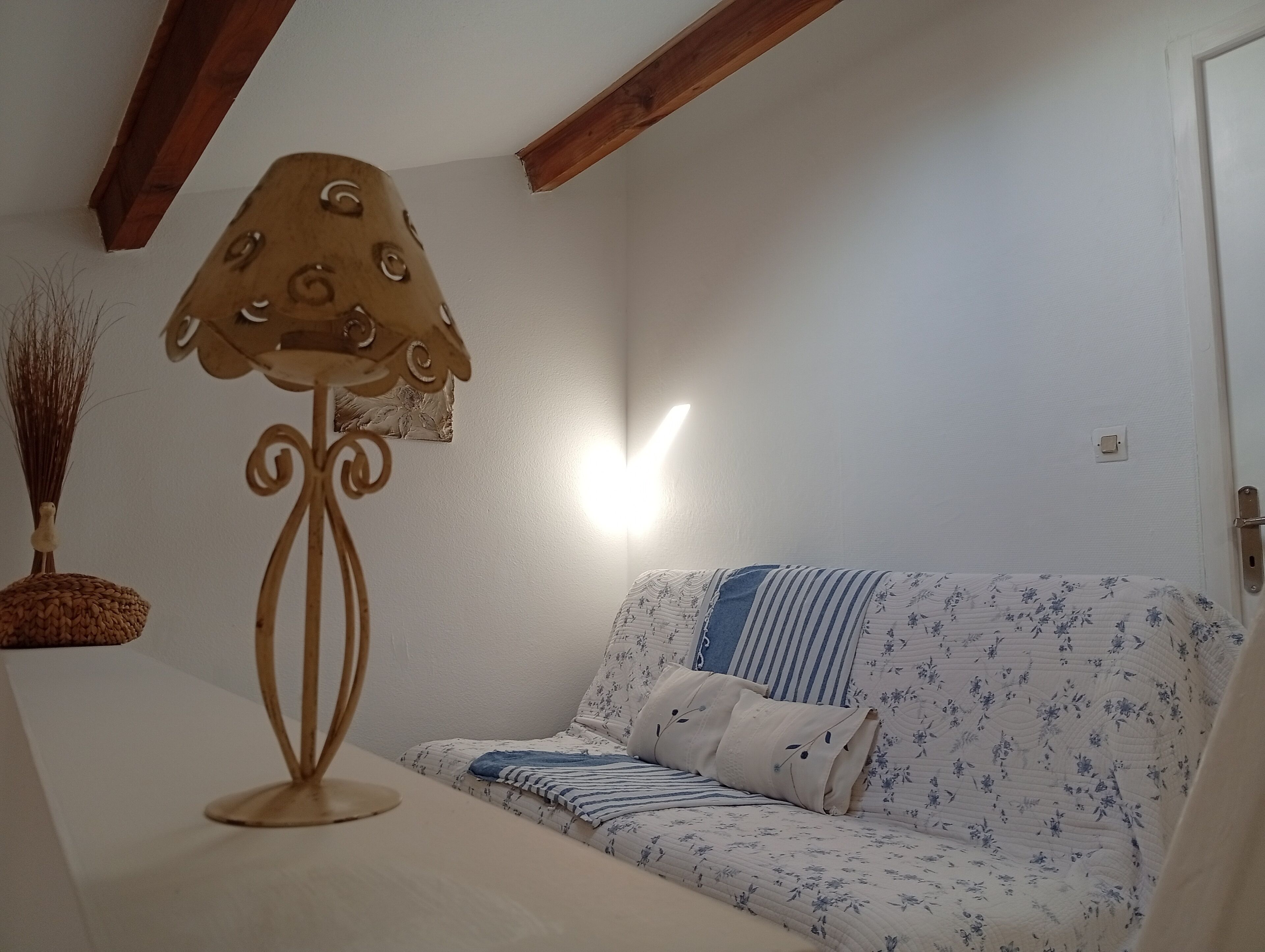 A room with a sofa, a lamp, and a wall-mounted light fixture.