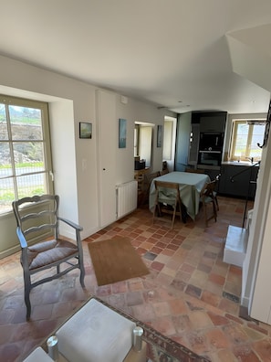A spacious room with a dining area, a kitchen, and a large window. - Cottage “La Maison Du Potager” with Private Terrace and Garden (Laps)