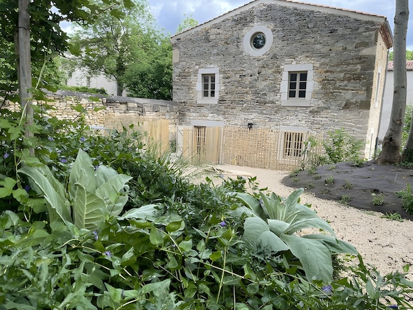 Un bâtiment en pierre doté de deux fenêtres et d’une fenêtre circulaire au-dessus de la porte.