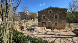 Un bâtiment en pierre doté d’un petit patio, d’une fenêtre ronde et d’une porte.