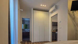A bedroom with a bed, a wardrobe, and an air conditioning unit. - Grey Pearl Suites - Green Pearl (Manfredonia)