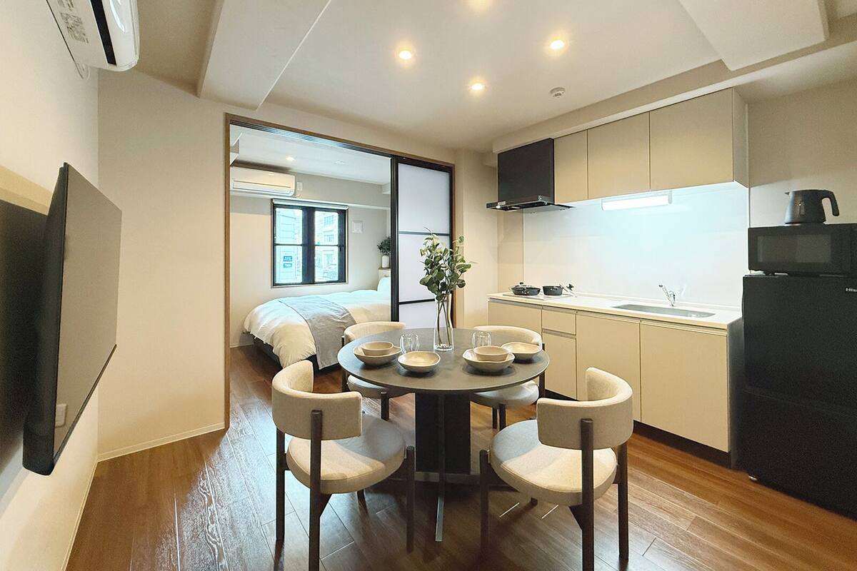 Un espacio habitable compacto con comedor, kitchenette y un dormitorio con ventana.