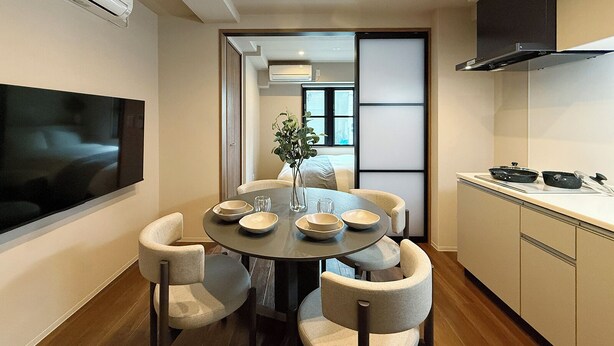 Una cocina moderna con una mesa de comedor, sillas y un televisor montado en la pared.