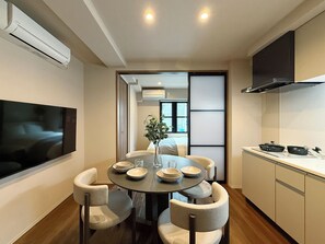 Una cocina moderna con una mesa de comedor, sillas y un televisor montado en la pared.