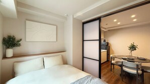 Una habitación de hotel moderna con cama, una mesa de comedor y una zona de cocina.
