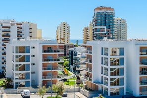 Ein moderner Apartmentkomplex mit mehreren Hochhäusern, Balkonen und freiem Blick auf das Meer.